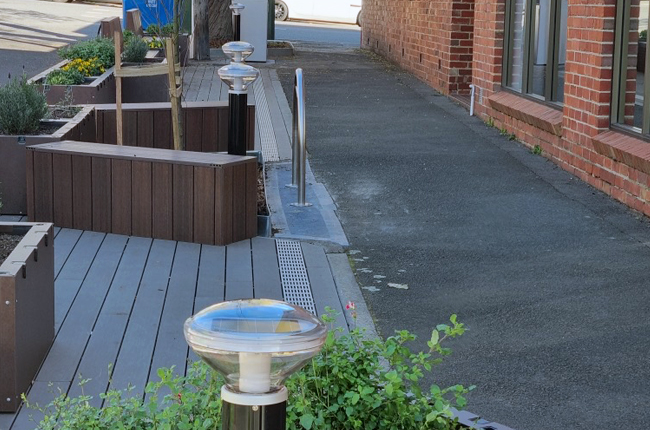Solar bollard light installed beside residential pathway near building entrance